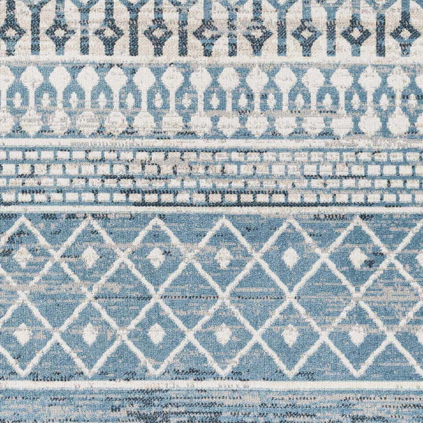 Close-up of the Pinamopoan Washable Area Rug. Features a geometric pattern in shades of blue, gray, and light beige. Swatch