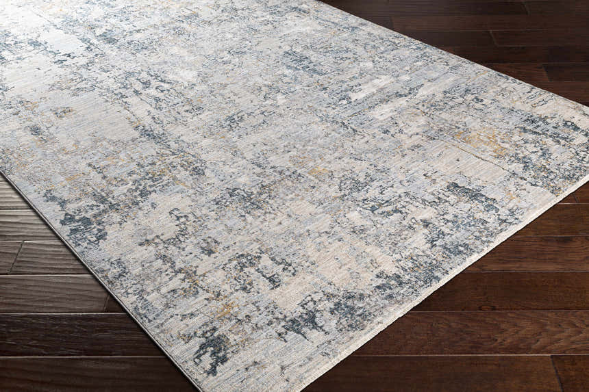 Close up of the Pinjarra Luxe Rug showing its charcoal, cream, and gray contemporary design on dark hardwood floors. Corner