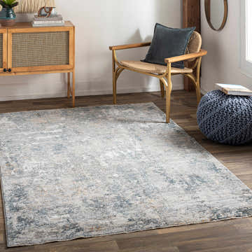 Living room scene with a Pinjarra Luxe Rug in charcoal, cream, and blue tones, styled with a wood cabinet and chair. Roomscene-Rectangle