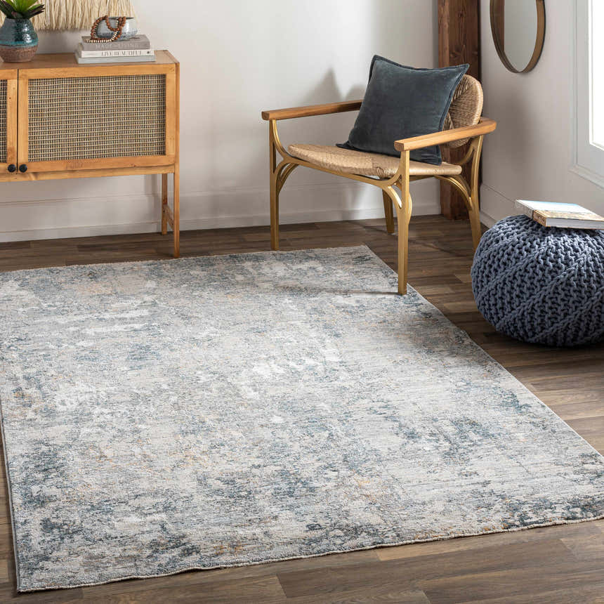 Living room scene with a Pinjarra Luxe Rug in charcoal, cream, and blue tones, styled with a wood cabinet and chair. Roomscene-Rectangle