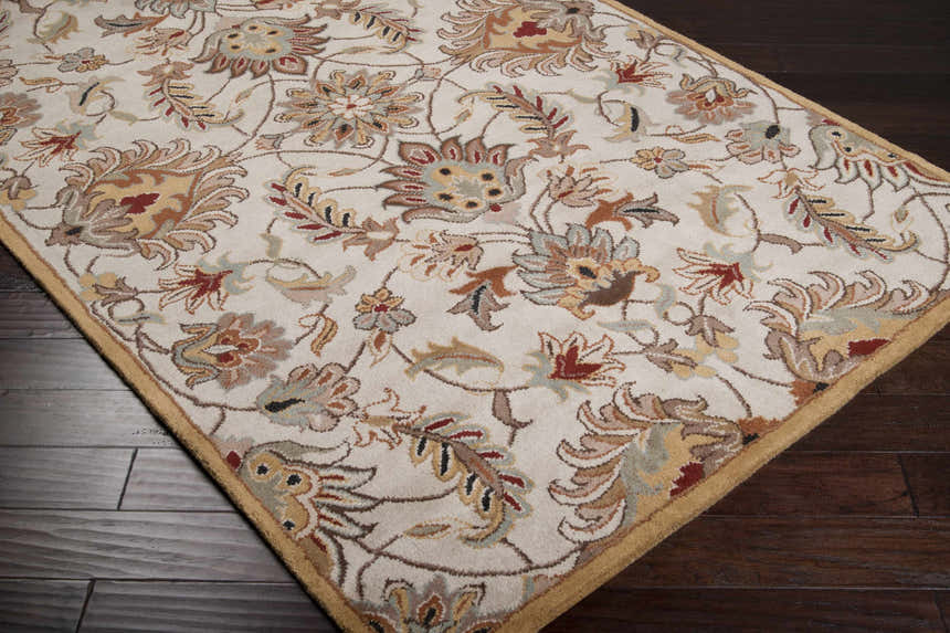 Close-up of the Pirtleville Area Rug showing its floral, traditional pattern and neutral colors on dark wood floors. Corner