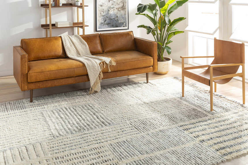 Living room scene with a brown leather sofa and a Plean Premium Rug in charcoal and cream. Roomscene-Rectangle