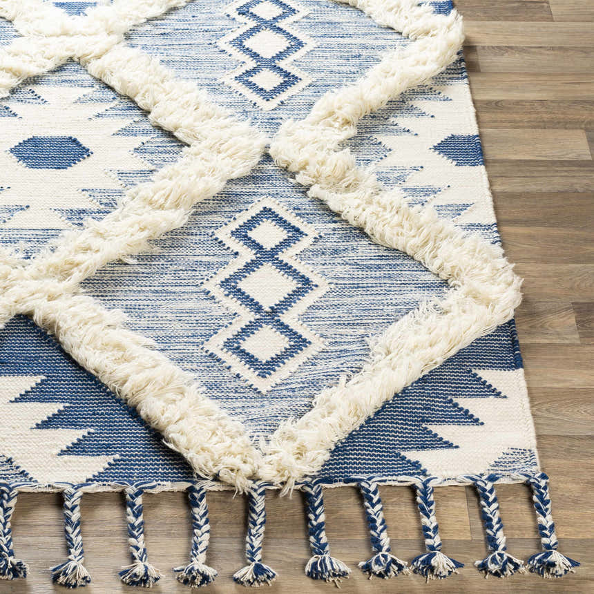 Close-up of the Painesdale Blue/White Wool Carpet, featuring a geometric diamond pattern with fringe and blue and white tassels. Front