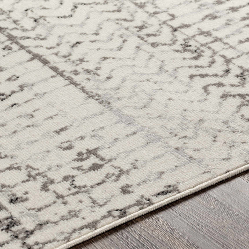 Close-up of the Priston Area Rug showing its off-white base with black, charcoal, and gray abstract pattern. Texture