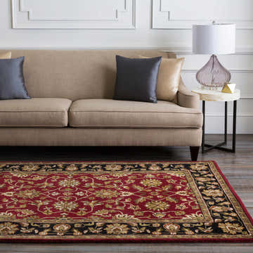 Living room scene with a Porthcawl Wool Area Rug in brick red and black. Beige sofa with gray pillows. Traditional style. Roomscene-Rectangle