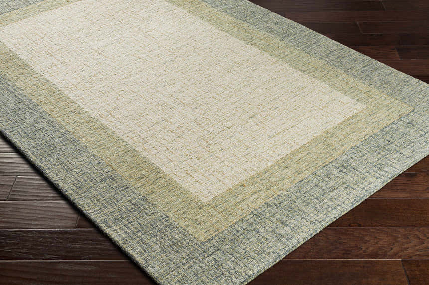 Close-up of the hand-tufted Pualas Area Rug. Cream, sage, and beige stripes on a textured 100% wool rug. Corner
