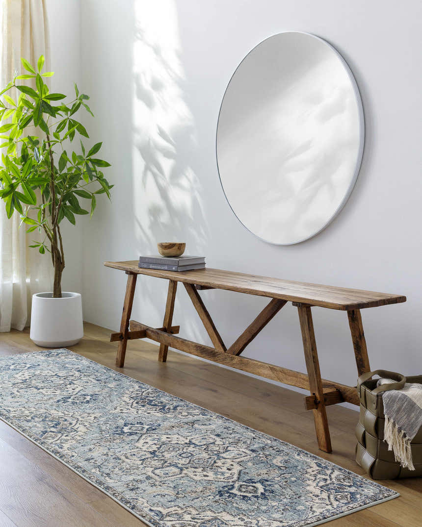 Entryway with a blue Pukwana Area Rug runner, wood bench, round mirror, and potted plant. Roomscene-Runner