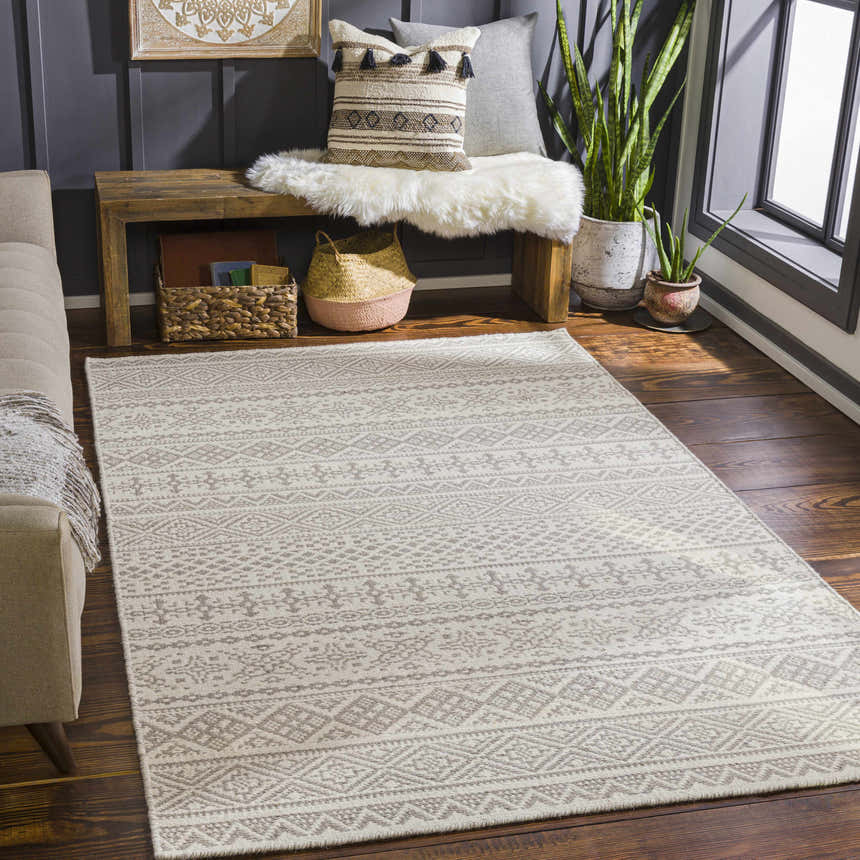Living room scene with a cream and gray Pumwani Area Carpet, wood bench, and dark gray accent wall. Roomscene-Rectangle