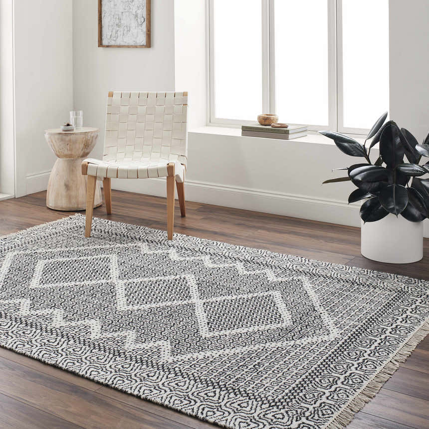 Bright living room with a bone and dark gray Rach Area Rug, woven chair, and wood accents. Roomscene-Rectangle