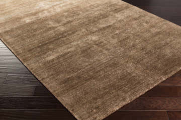 Close-up of the Reigate Area Rug showcasing its soft brown viscose texture and hand-woven construction on dark wood floors. Corner