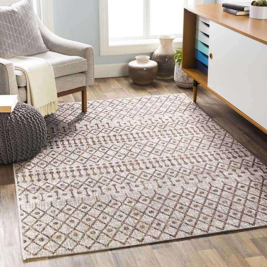 Living room scene with a brown and white Rennert Area Rug, gray chair, and wood cabinet. Roomscene-Rectangle