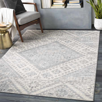 Living room scene with a gray chair and the Renton Area Rug in gray, ivory, and silver gray. Roomscene-Rectangle