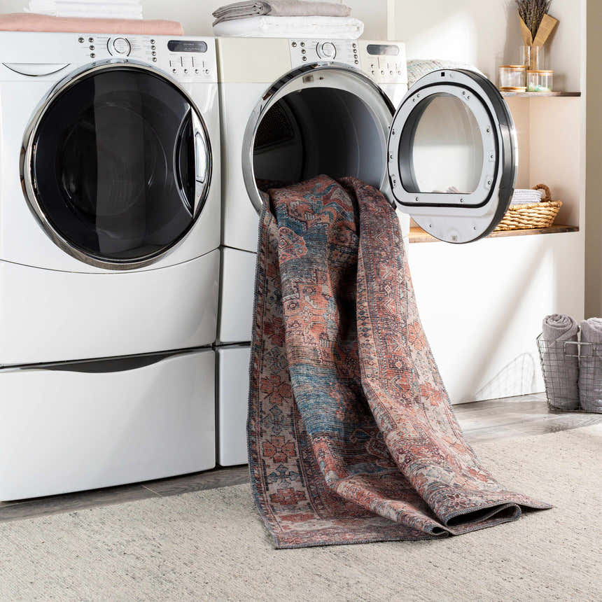 Laundry room scene with Baltinglass Rust & Blue Washable Area Rug coming out of the dryer. Easy to clean rugs. Washing-Machine