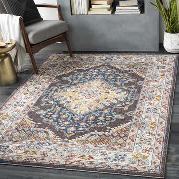 Living room scene with a Haymond Brown Medallion Area Rug, gray chair, gold side table, and dark wood floors. Roomscene-Rectangle