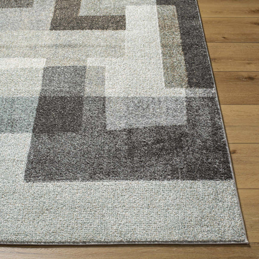 Close-up of Raisa Area Rug showing a contemporary geometric pattern in aqua, black, cream, gray, and light brown on wood floor. Front