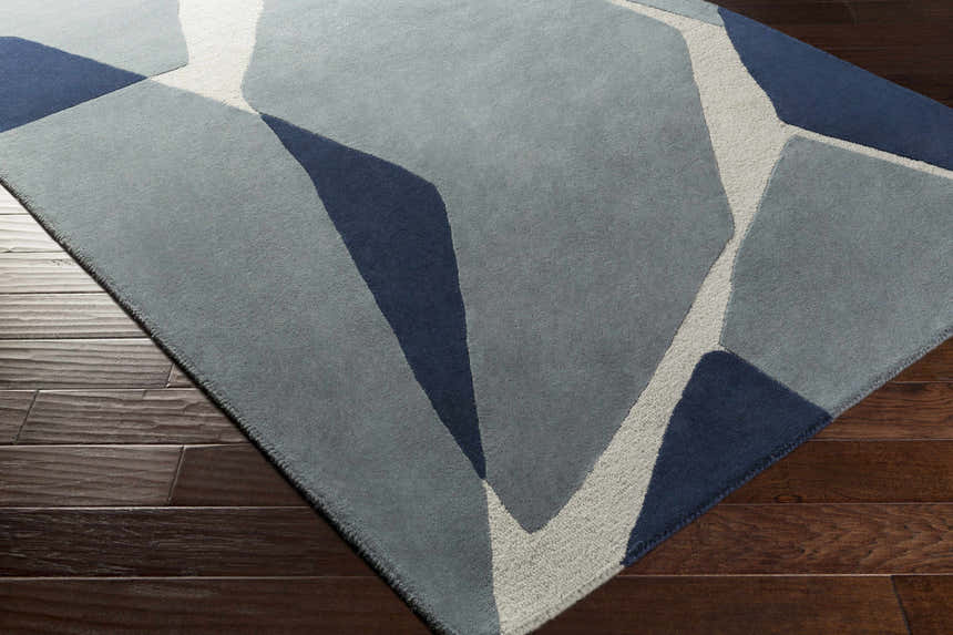 Close up of the Robbins Modern Blue Wool Rug featuring a geometric pattern in blue, light slate, and navy. Corner