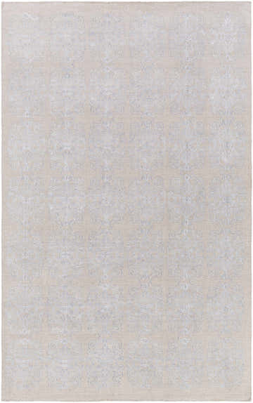 Close-up of the Ronceverte Area Rug showing a subtle, light blue floral pattern on a beige, hand-woven wool texture. Design-Rectangle-527