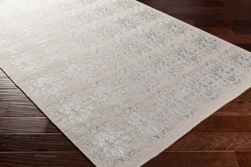 Close-up of the Ronceverte Area Rug, a hand-woven wool rug with a light beige background and silver floral pattern. Corner