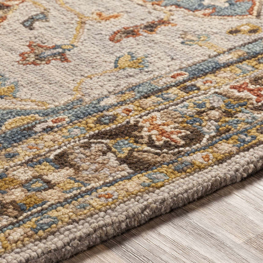 Close-up of the hand-tufted Rozel Area Rug. Features a traditional design with brown, teal, and mustard floral patterns. 100% wool. Texture