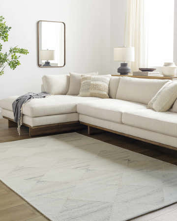 Living room scene with a pearl Rakin Ivory Area Rug, white sectional sofa, wood floors, and neutral decor. Roomscene-Rectangle