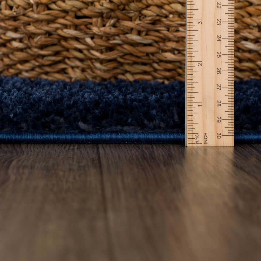 Close-up of the Navero Dark Blue rug showing its plush texture and precise edge binding, with a ruler for scale. Pile