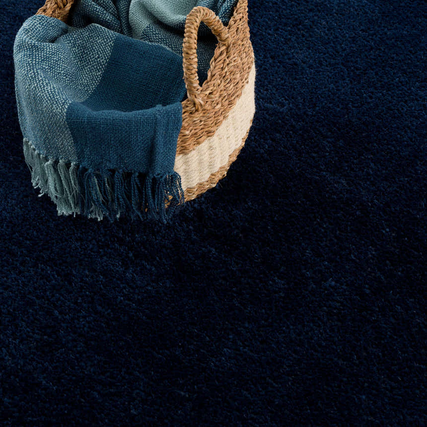 Close-up of the Navero Dark Blue rug with a basket and blue fringed throw blanket. Soft texture. Styleshot