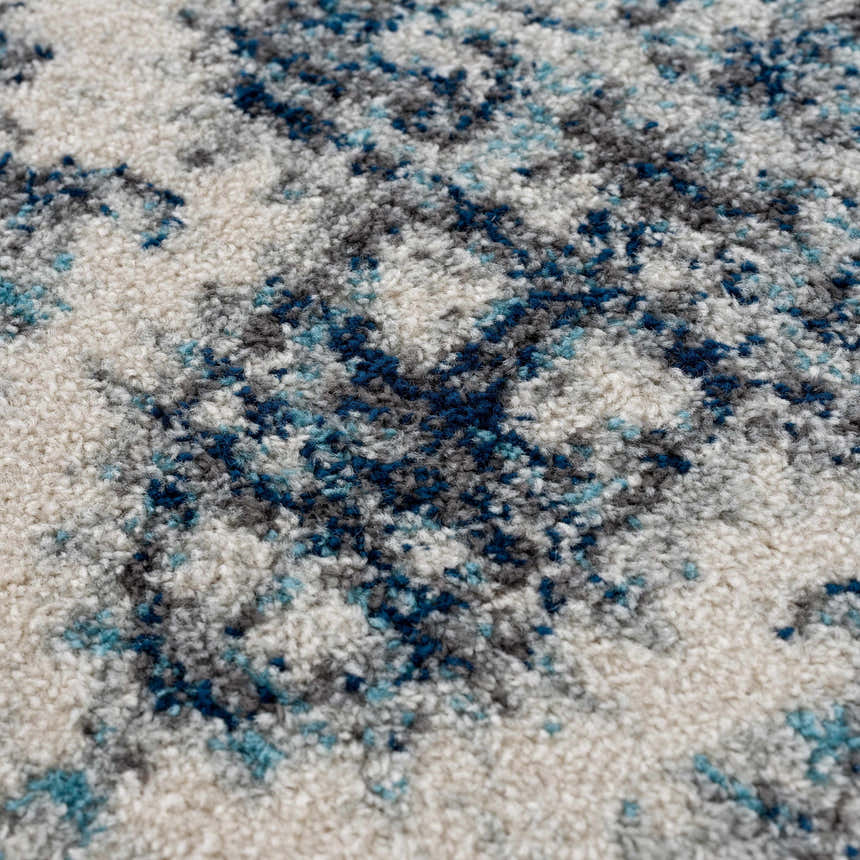Close-up of the Istanbullu Blue Area Rug showing its ivory, silver gray, and blue abstract pattern and soft texture. Texture