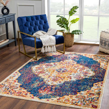 Living room scene with a blue velvet chair on the Istanbul Navy Area Rug. The rug features a traditional vintage design. Roomscene-Rectangle