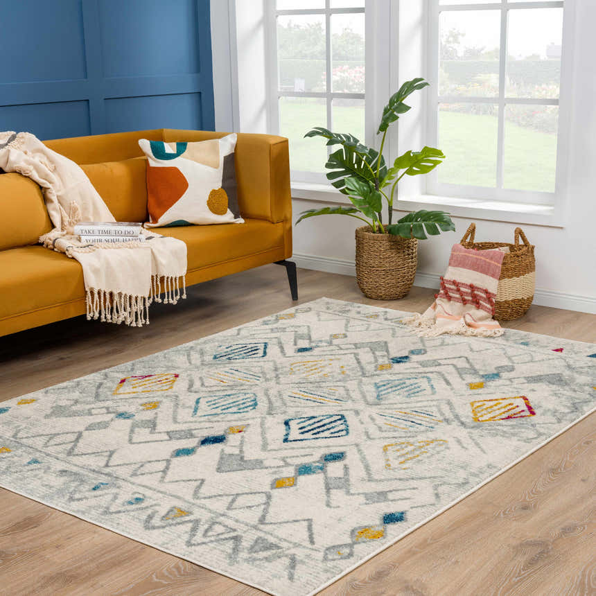 Living room scene with mustard sofa and Istanbul Aztec Area Rug in light gray, blue, and mustard. Roomscene-Rectangle