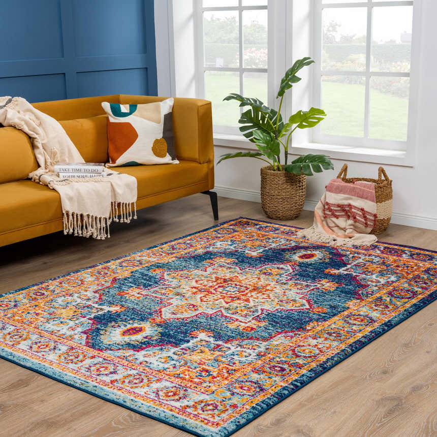 Living room scene with Istanbul Medallion Blue & Orange rug, mustard sofa, and blue accent wall. Bright, bohemian style. Roomscene-Rectangle