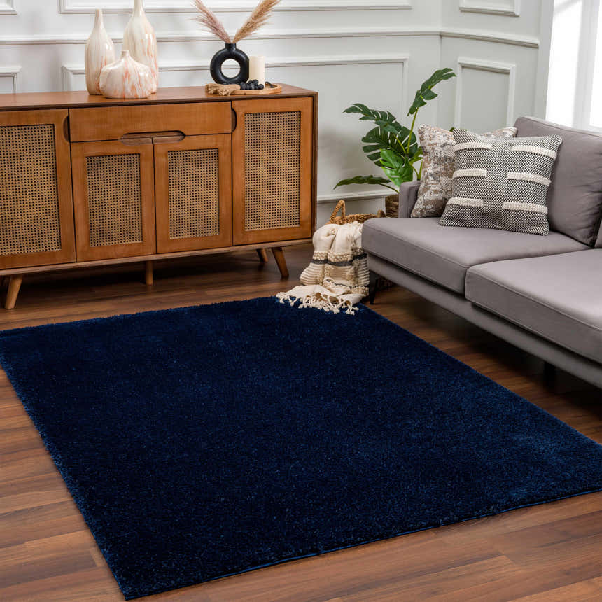 Living room scene with a Navero Dark Blue rug, wood cabinet, gray sofa, and hardwood floors. Roomscene-Rectangle