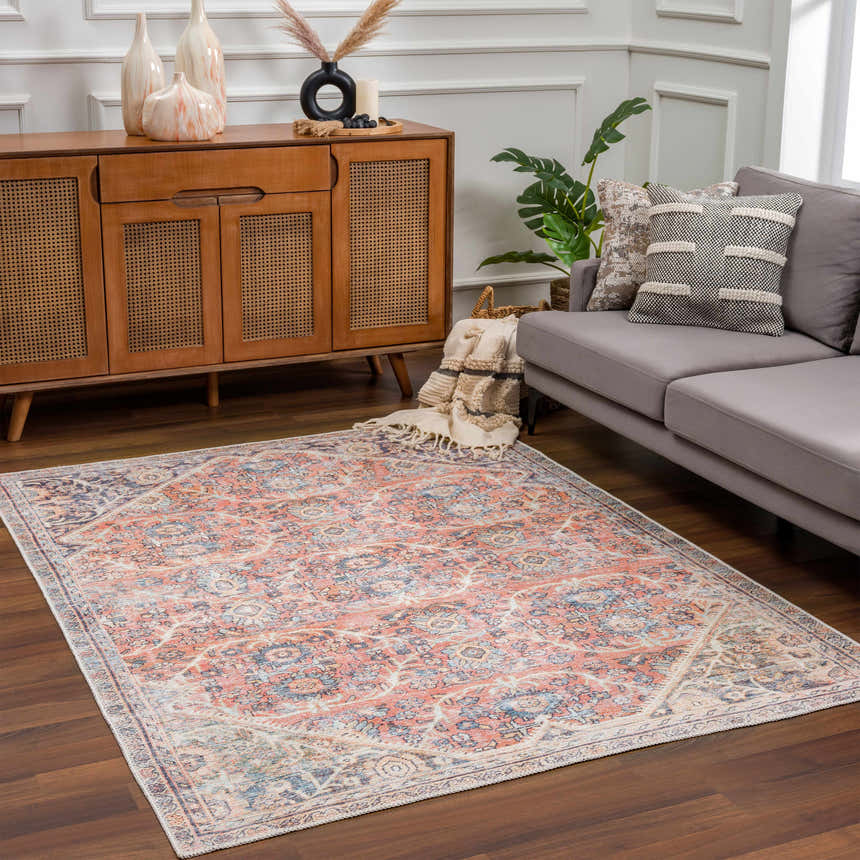 Living room scene with a Konstantina Washable Area Rug in peach, blue, and beige, styled with a gray sofa and wood cabinet. Roomscene-Rectangle