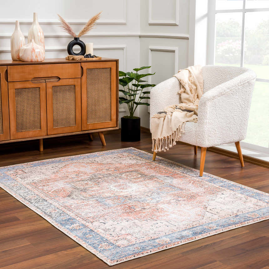 Living room scene with a beige armchair, wood cabinet, and Rosman Distressed Washable Area Rug in beige, blue, and brick red tones. Roomscene-Rectangle