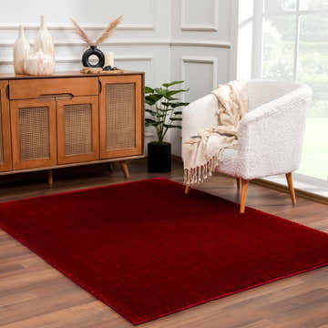 Living room scene with a Heavenly Solid Red Plush Rug, wood cabinet, and white boucle chair. Roomscene-Rectangle