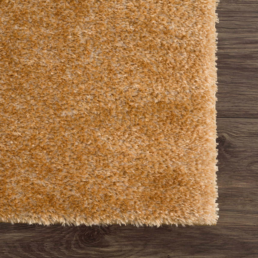 Close-up of the Heavenly Solid Mustard Plush Rug showing its soft texture and color on dark wood flooring. Swatch