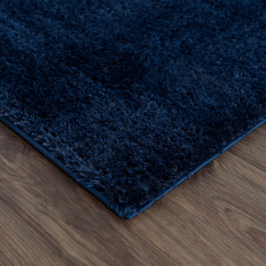 Close up of the Navero Dark Blue shag rug showing the texture and color on a wood floor. Corner