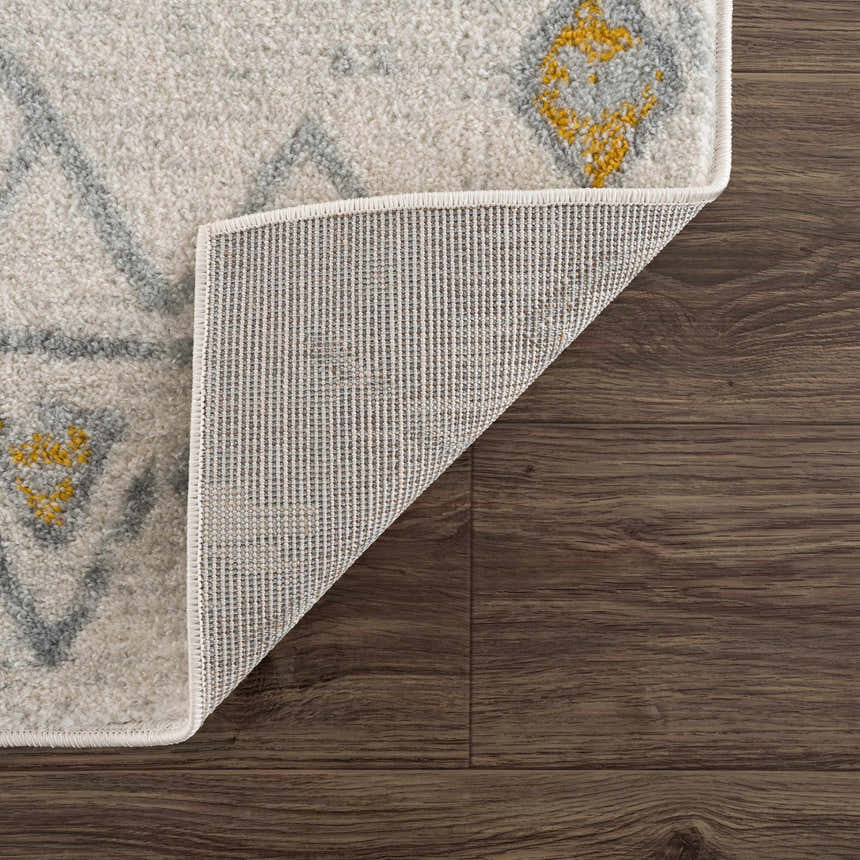 Close-up of the Istanbul Aztec Area Rug showing off-white, gray, and mustard geometric design and rug backing. Fold