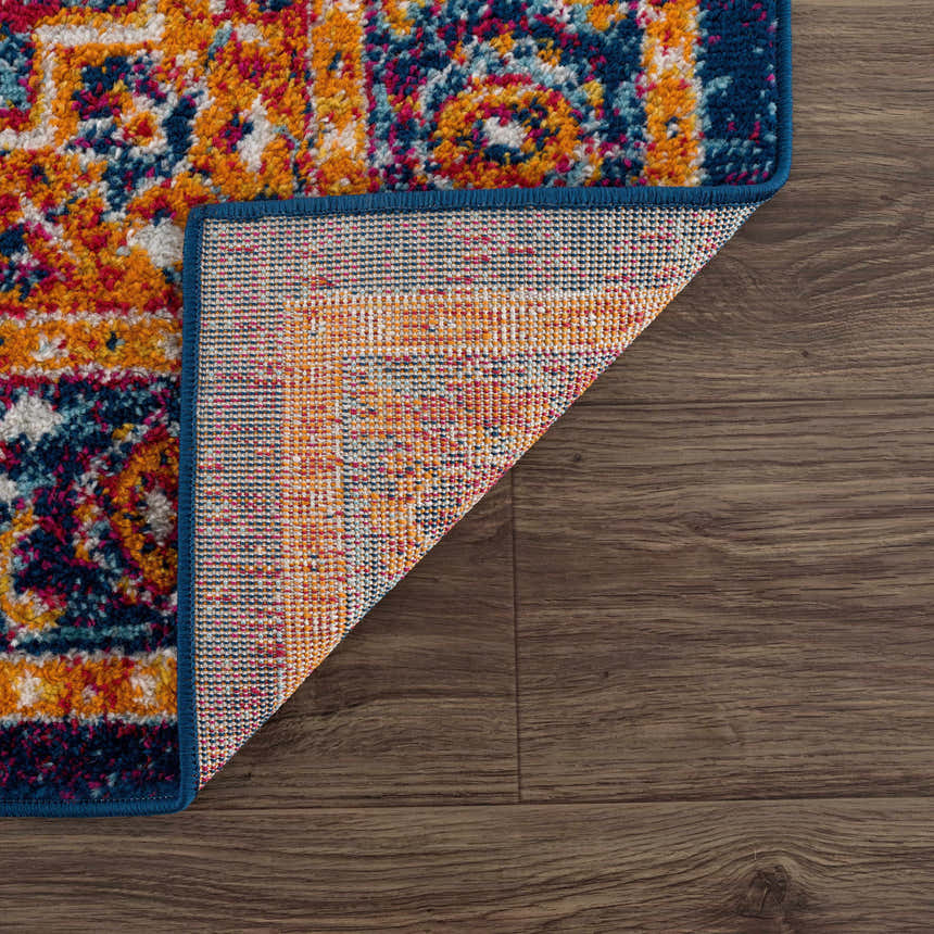 Close-up of the Istanbul Medallion Blue & Orange Area Rug showing the navy, turquoise, and orange bohemian pattern. Fold