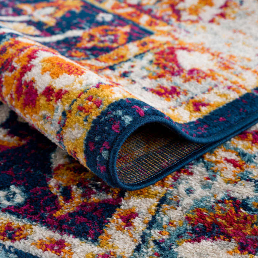 Close-up of the Istanbul Vintage Navy Area Rug showing its ivory, navy, pink, and gold bohemian pattern. Fold