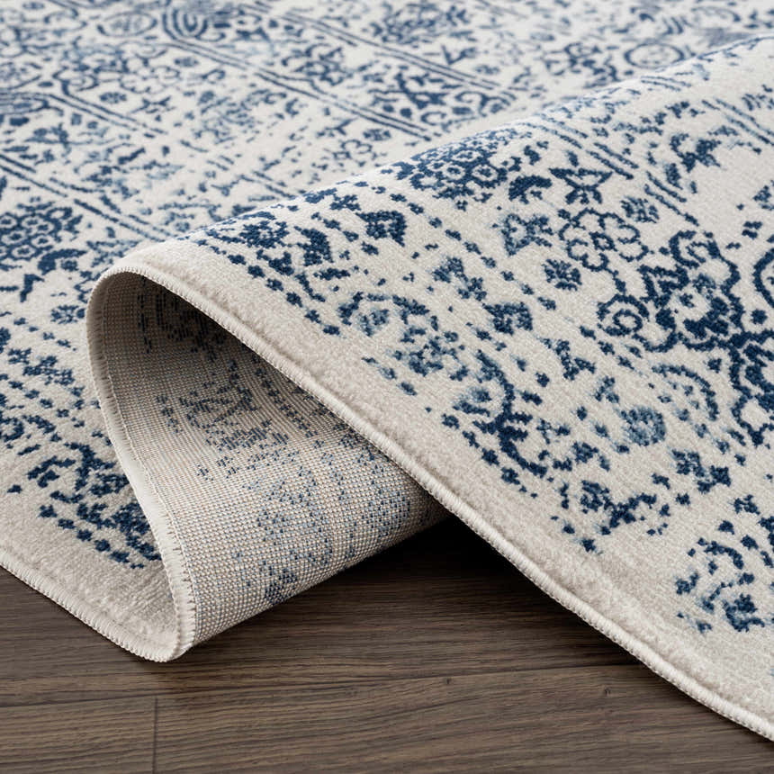Close-up of the Michie Blue Area Rug showing its dark and light blue bohemian pattern and machine-woven texture. Fold