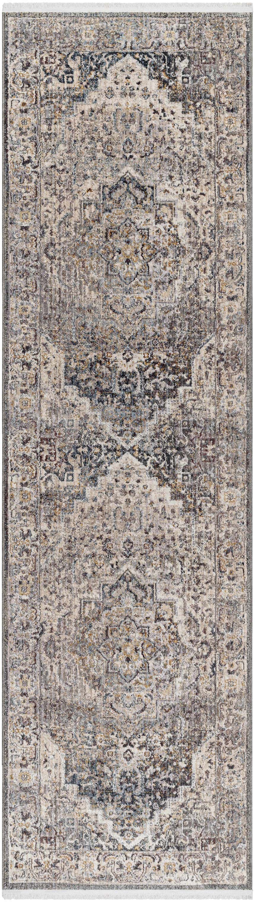 Close-up of the Rada Area Rug. Beige, camel, and charcoal traditional rug with a distressed pattern and fringe. Design-Runner-279