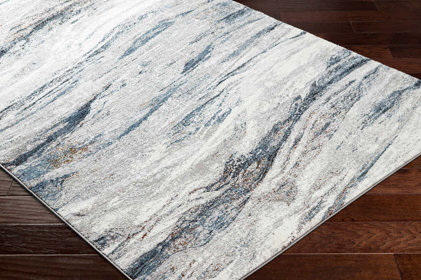 Close-up of the Glain Gray & Blue Marble Area Rug showing its abstract pattern and colors on dark wood flooring. Corner