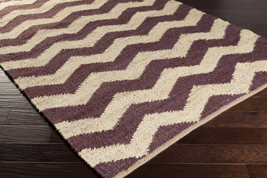 Close-up of the Saginaw Jute Carpet showing a beige and dark purple zig-zag pattern and hand woven texture. Corner