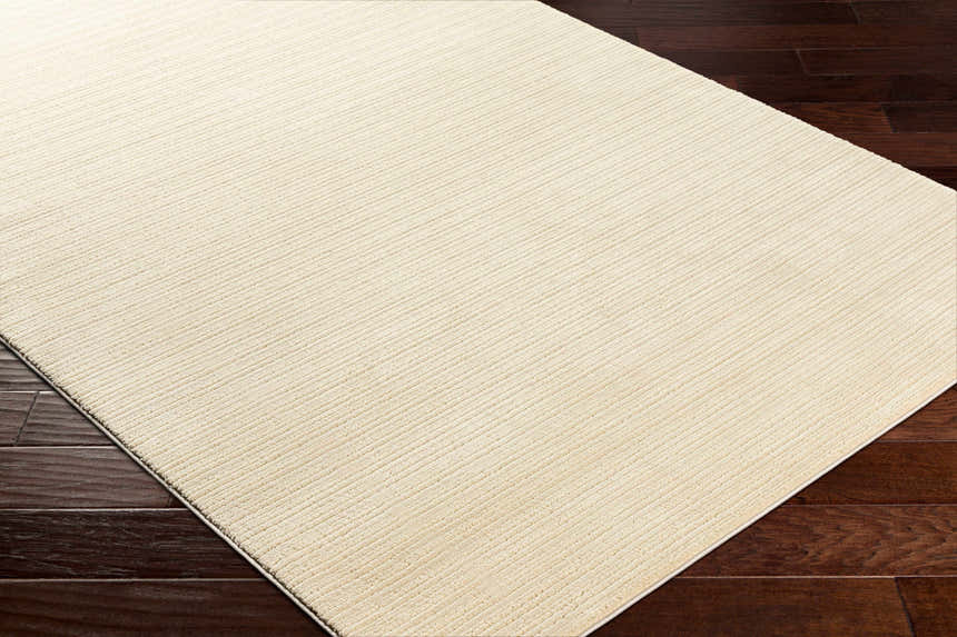Close-up of a Lambswool Kini Plush Textured Washable Rug showing its plush texture and subtle striped design on dark wood floors. Corner