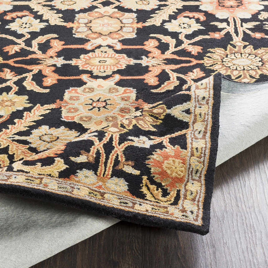 Close-up of the hand tufted Salix Black Wool Rug, showcasing its floral design and rich colors. Fold