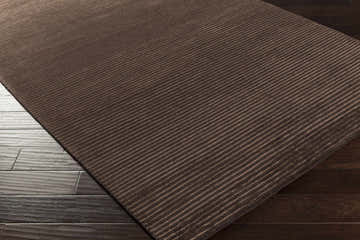Close-up of the brown Sanatoga Area Rug showing its subtle striped pattern and hand-knotted texture. Corner