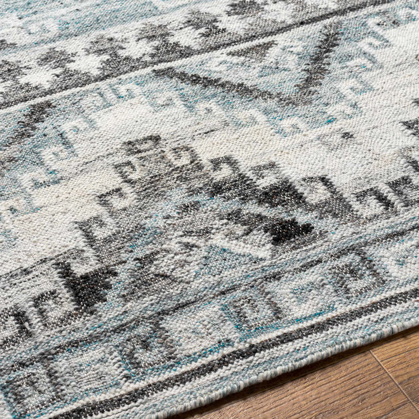 Close up of Binda Area Rug. Geometric design in blue, dark brown, gray, ivory, and slate blue. Hand woven texture. Texture