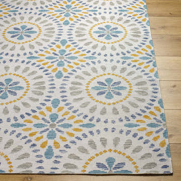 Close-up of the Karin Area Rug. Light gray rug with coastal-inspired blue, gray, and gold floral medallion pattern. Front