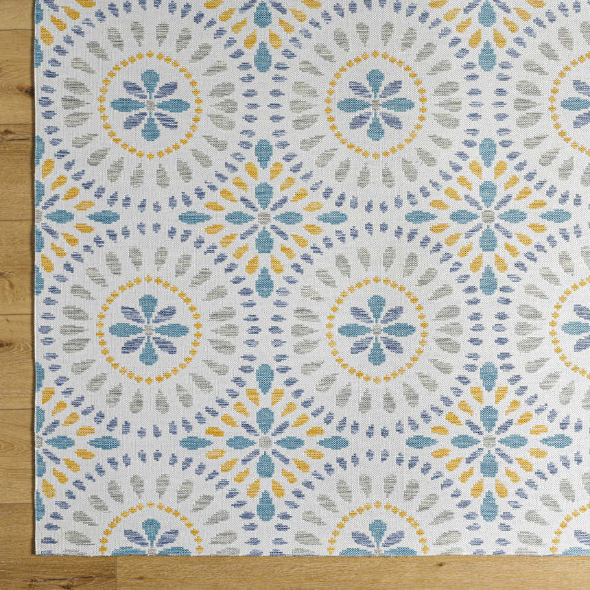 Close-up of the Karin Area Rug, a light gray rug with a coastal-inspired blue, gold, and gray floral medallion pattern. Corner