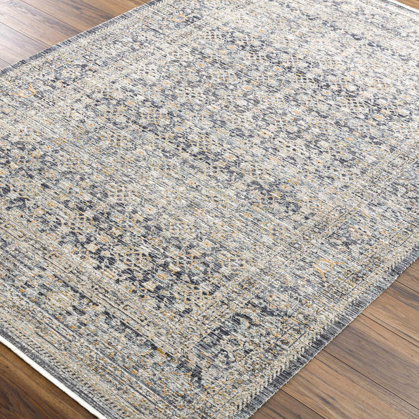 Close-up of the Margaret Navy Washable Rug. Becki Owens x Livabliss rug with a traditional design in ash, gray, and silver tones. Corner